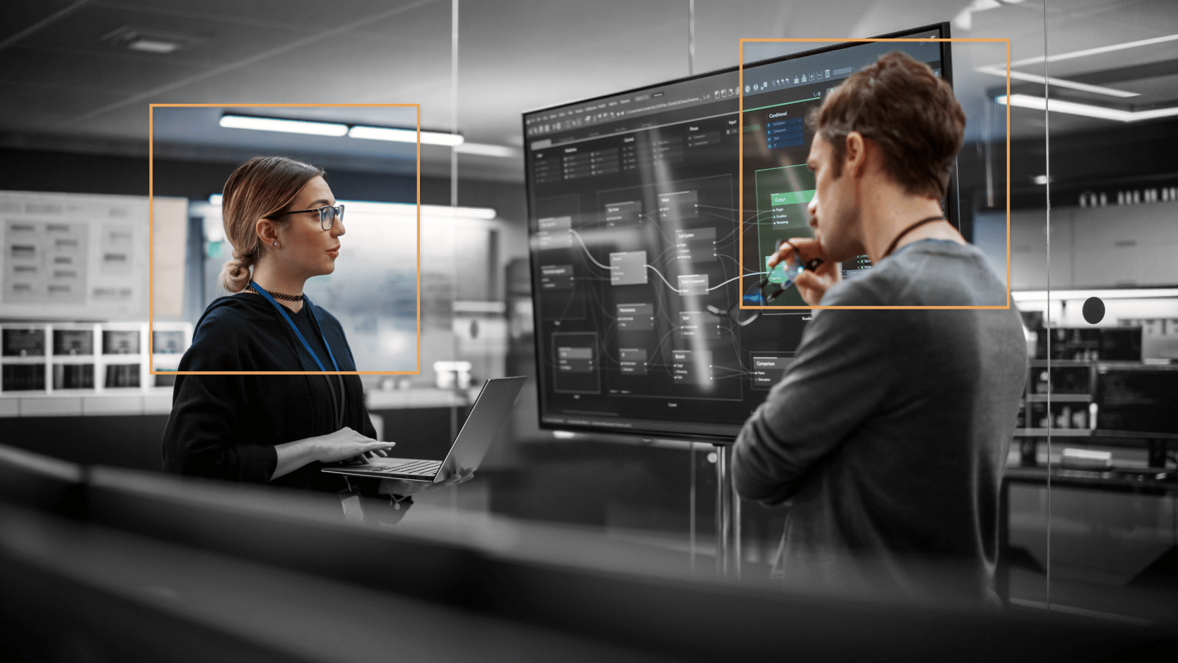 Zwei Fachleute arbeiten mit KI-Erkennungs-Overlays in einem modernen Tech-Büro und veranschaulichen so die KI-gesteuerte Transformation des Arbeitsplatzes.